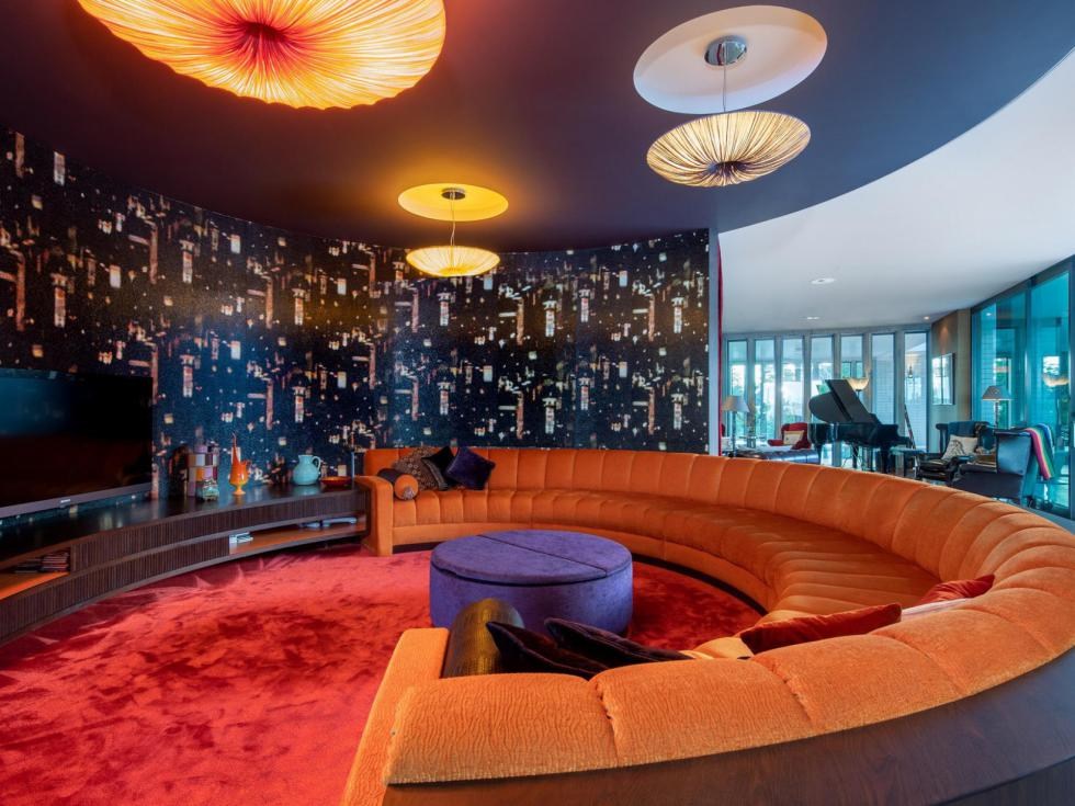 Curved orange sofa and city-lights wallpaper in the media lounge of the Martins Bay home