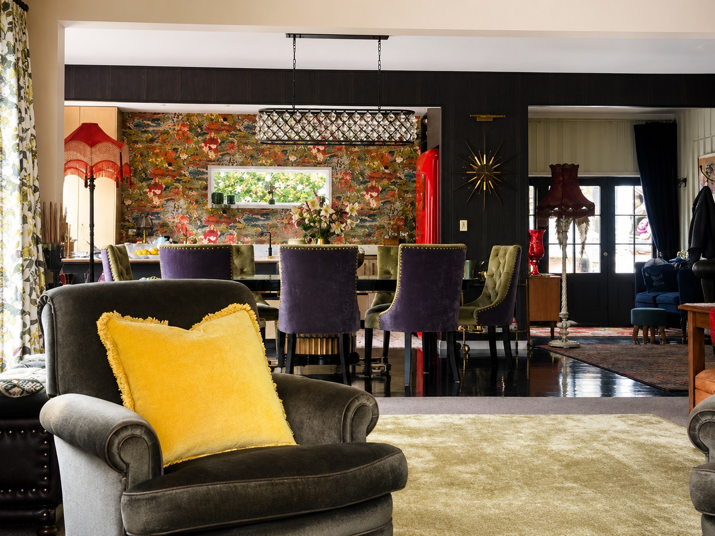 Rich open-plan dining room with olive velvet chairs and botanical wallpaper