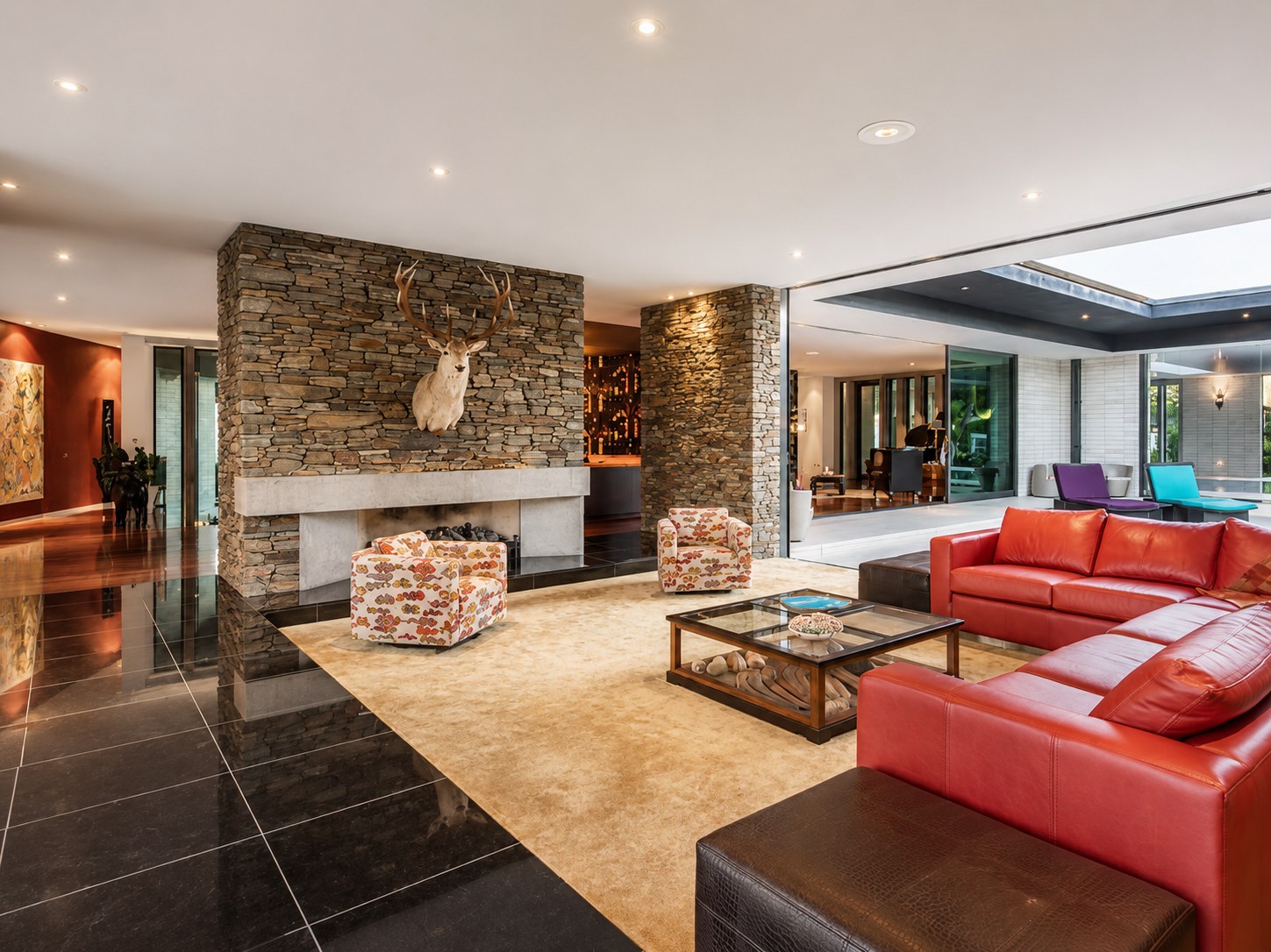 Grand living room with stacked-stone fireplace and red leather sofas